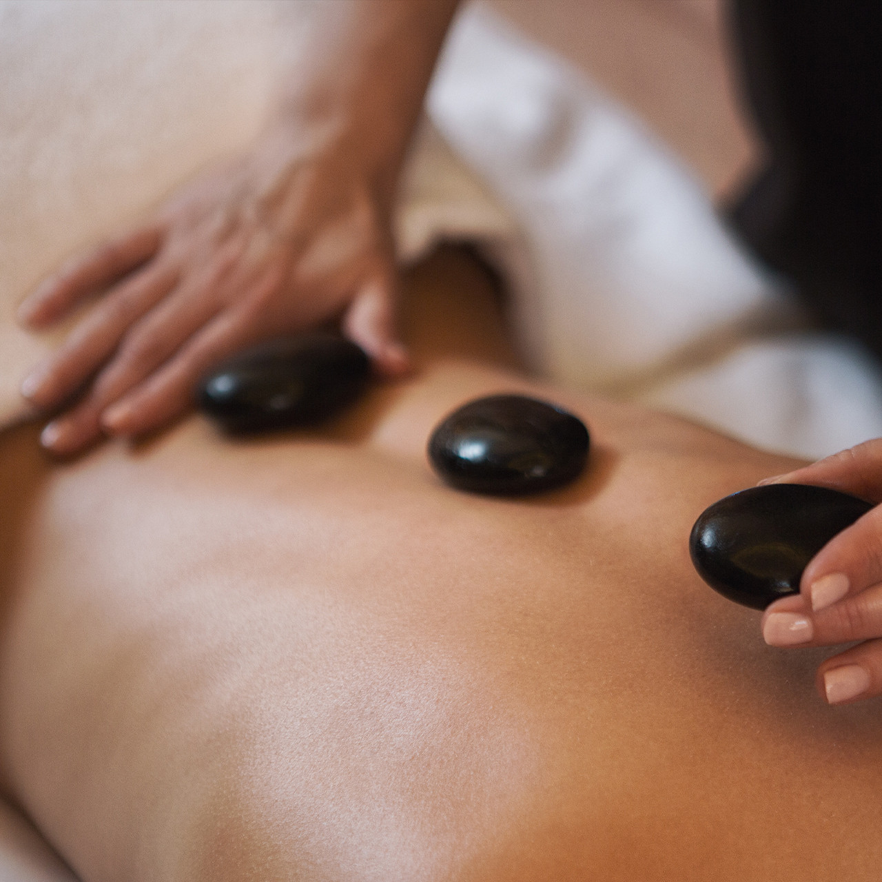 Vrouw ligt op buik tijdens een hotstone massage en geniet